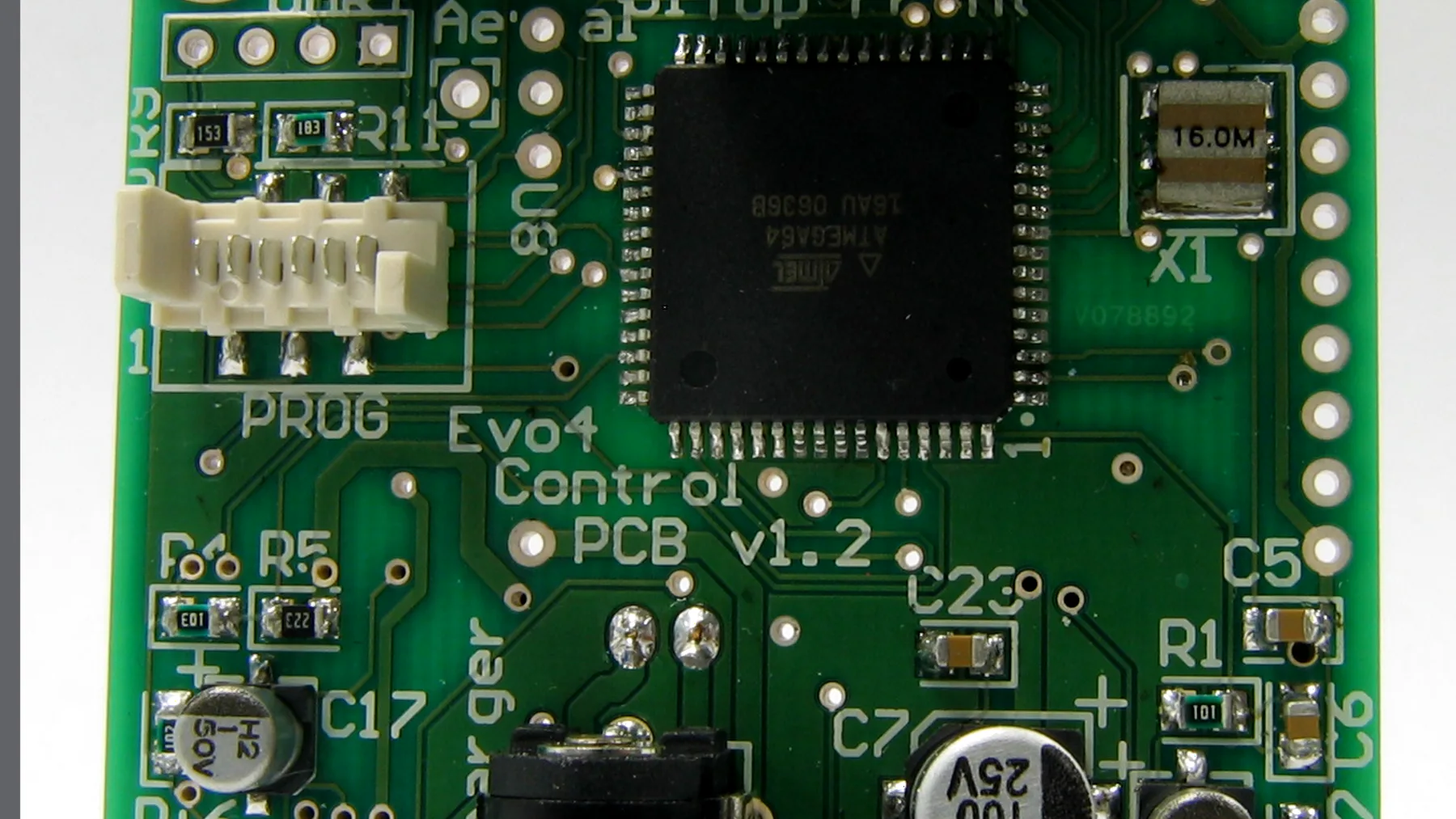 Close-up of a soldering iron working on a small SMD capacitor on a PCB