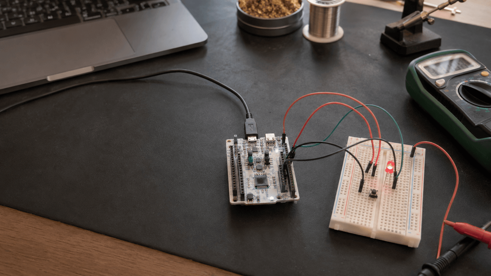 STM32 Nucleo board wired to an LED and push button on a practical electronics workbench