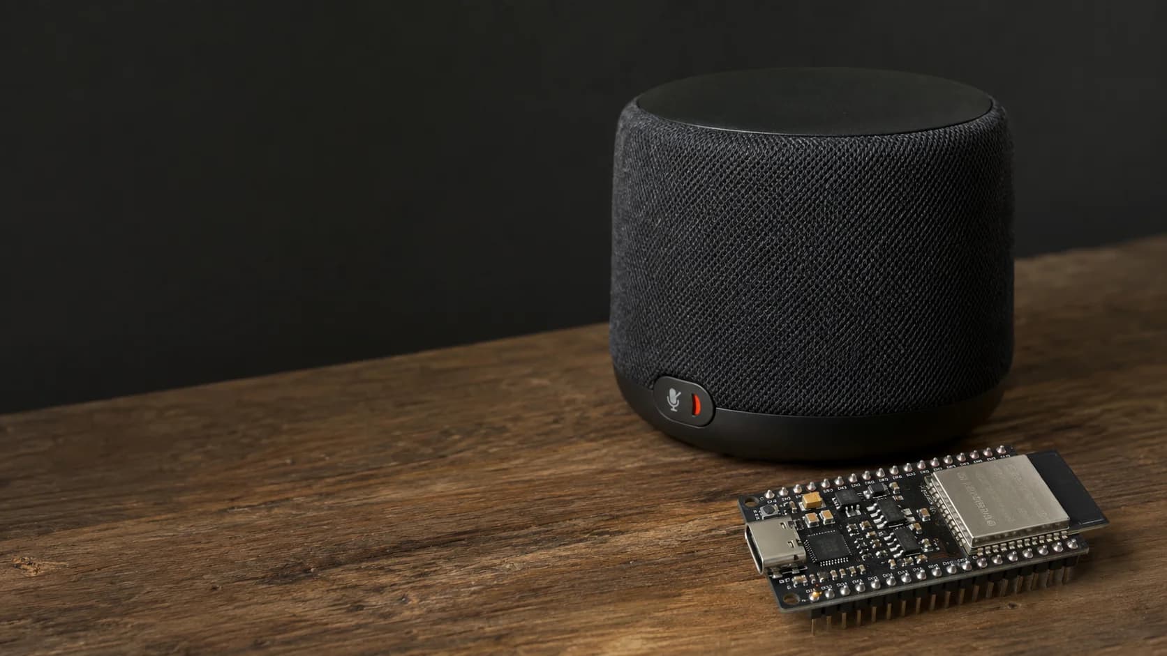 Realistic smart speaker prototype beside an ESP32-S3 board and laptop with audio waveforms