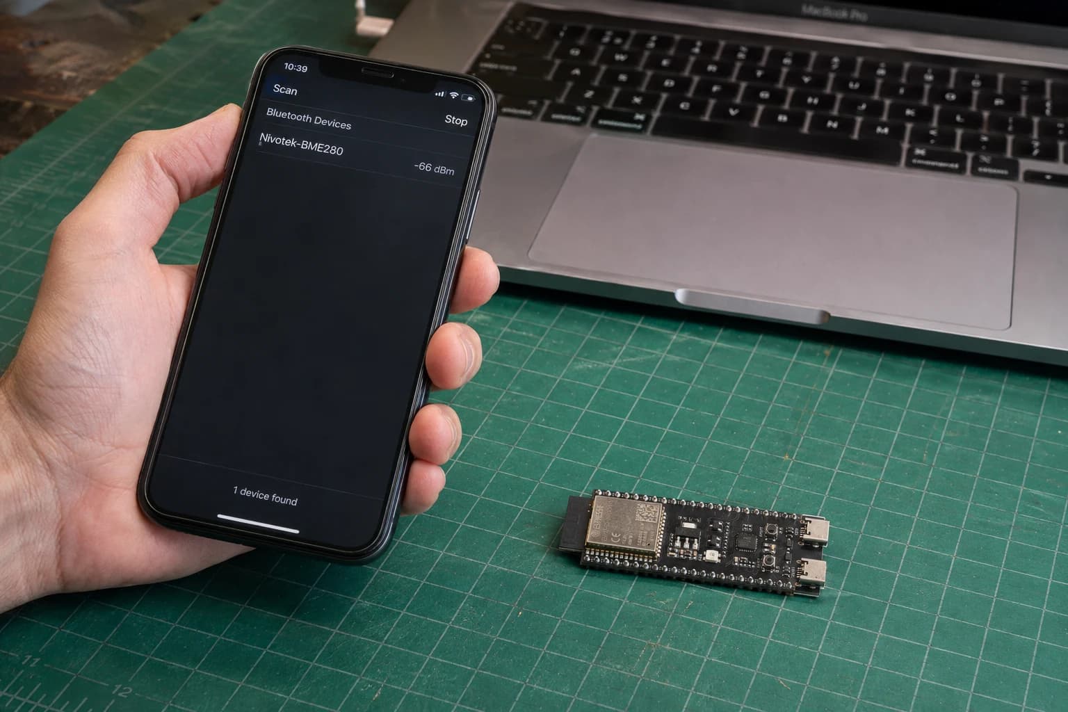 Điện thoại quét thiết bị BLE Nivotek-BME280 phát từ ESP32-S3 DevKitC-1 bên cạnh MacBook Pro.
